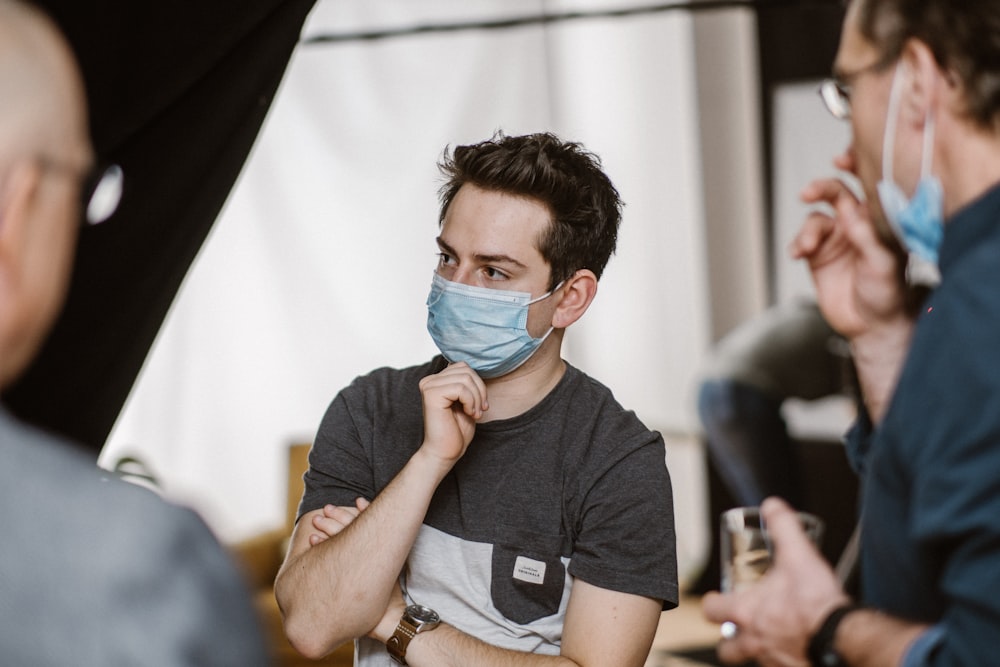 a man wearing a face mask while talking to another man