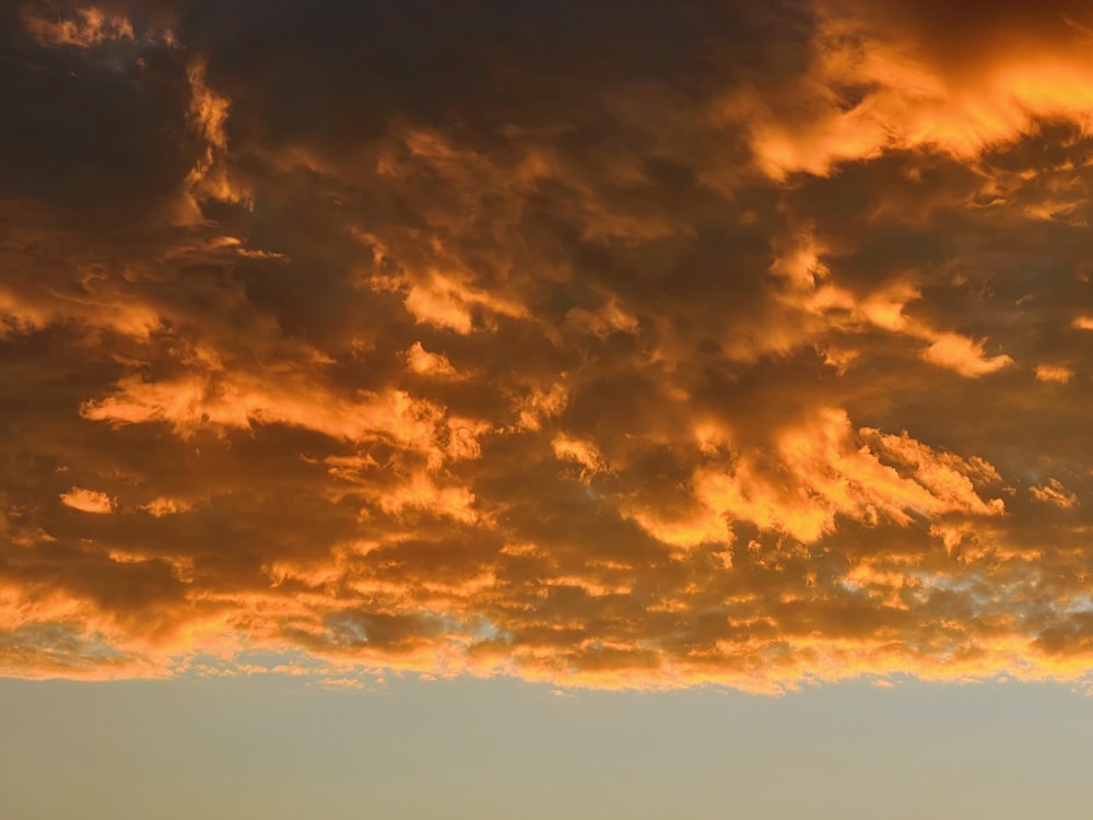 a plane flying through a cloudy sky at sunset