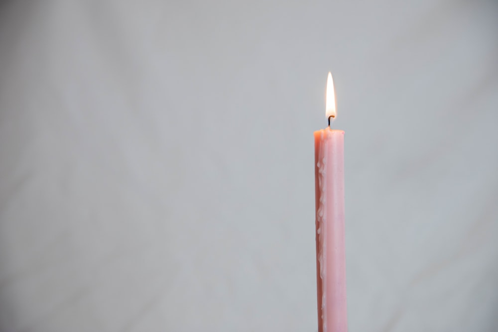 a single pink candle with a white background