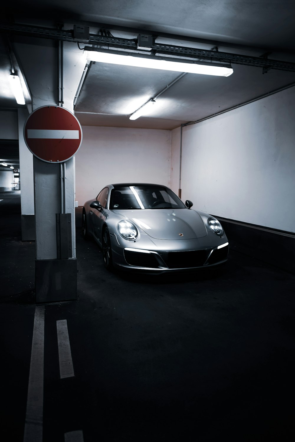 a car parked in a parking garage next to a no parking sign