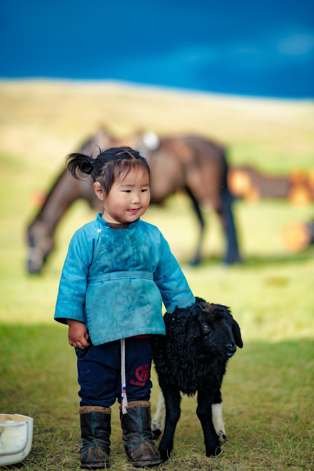 a little girl standing next to a black dog