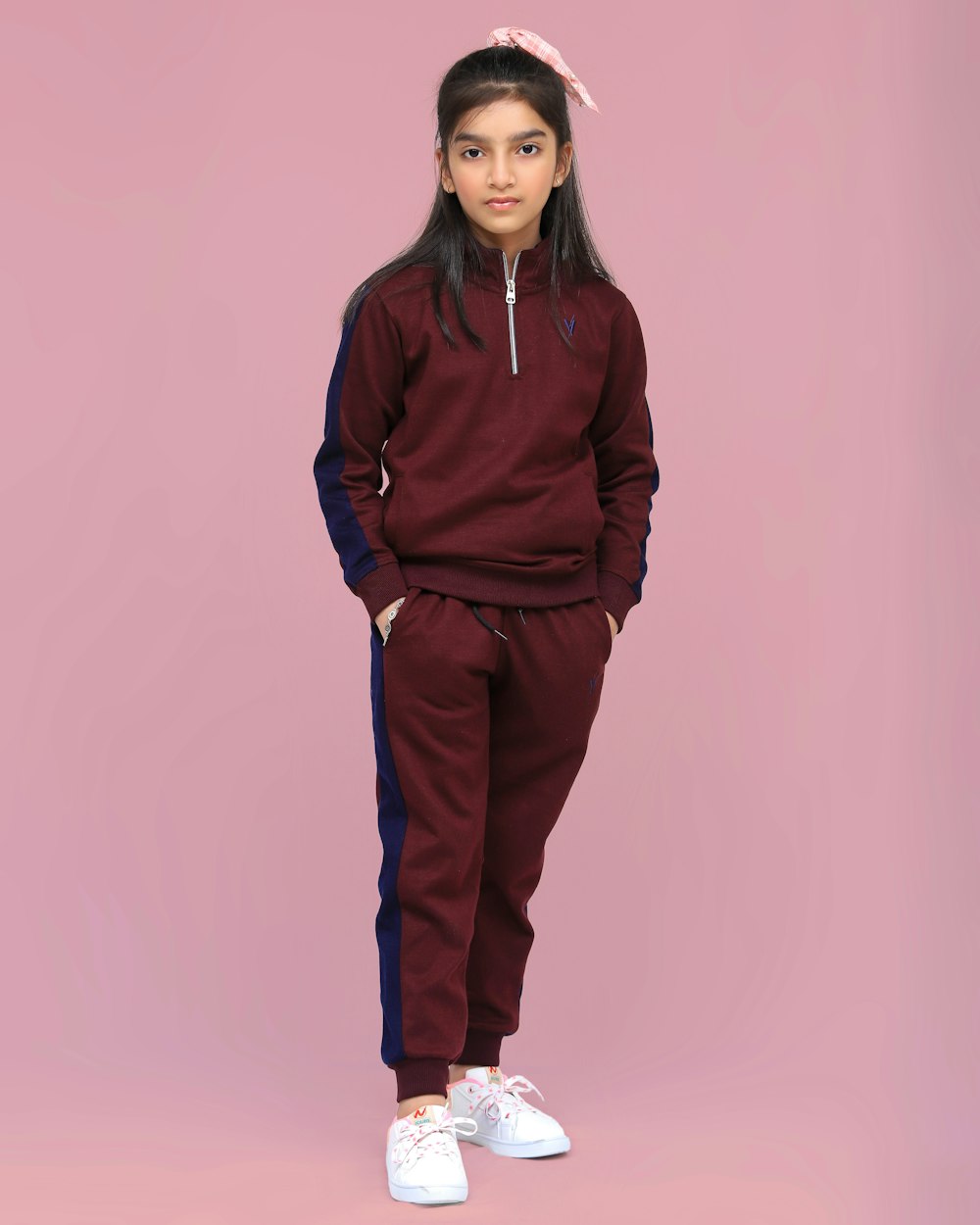 a young girl wearing a maroon and blue sweat suit