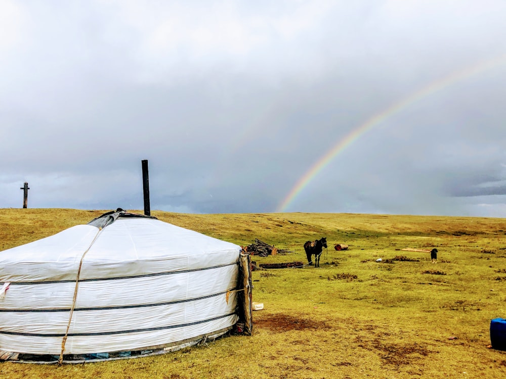 a rainbow is in the sky over a yurt