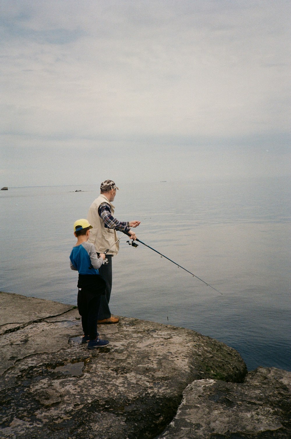 a man holding a fishing rod while standing next to a little boy
