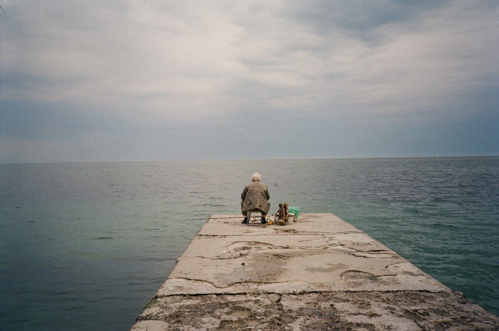 a man sitting on a pier next to a dog