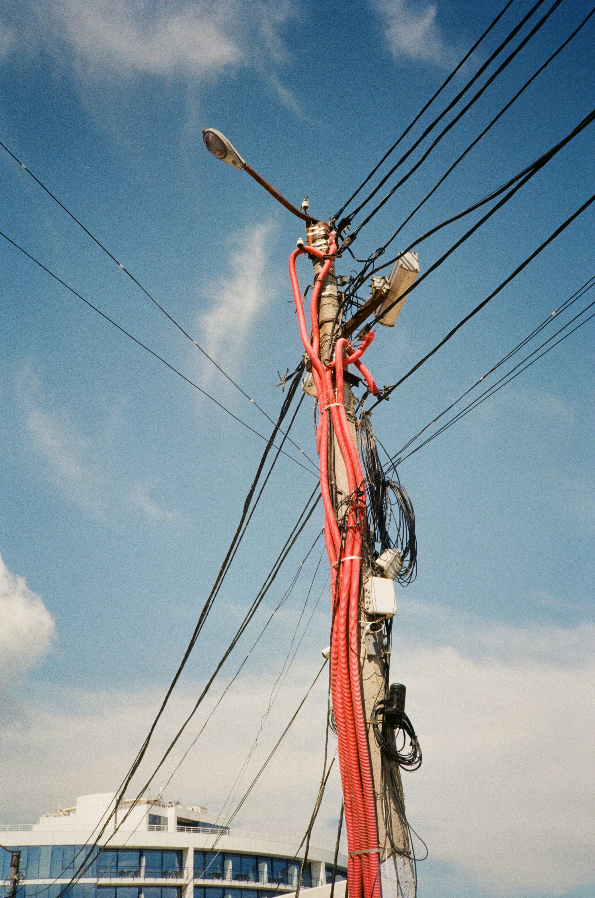 a pole with many wires and a building in the background