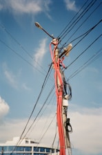 A technician installing fiber optic cables in a modern urban neighborhood under a clear blue sky.