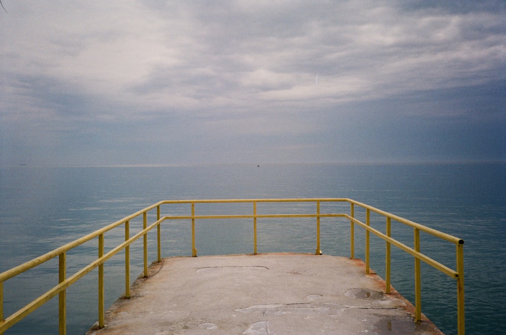 a yellow railing on the side of a large body of water