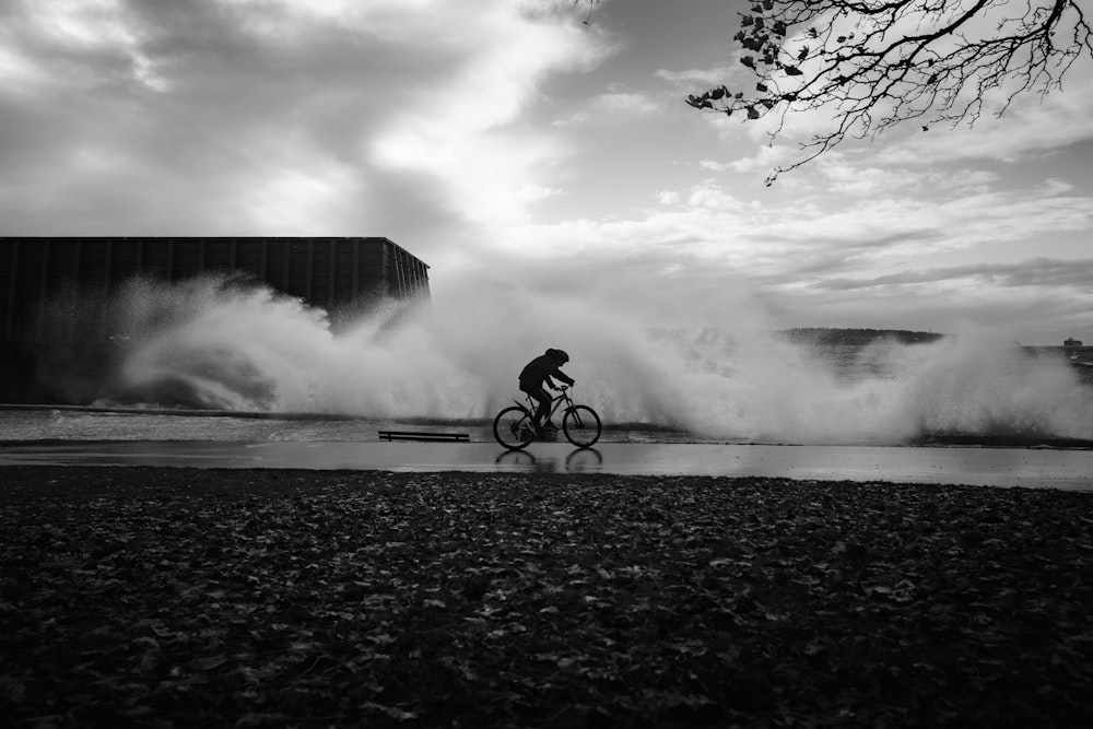 a man riding a bike past a large wave