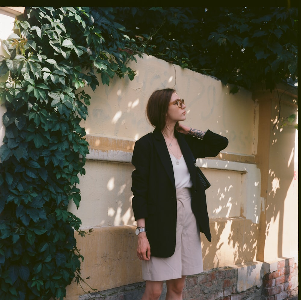 a woman leaning against a wall with her hand on her head