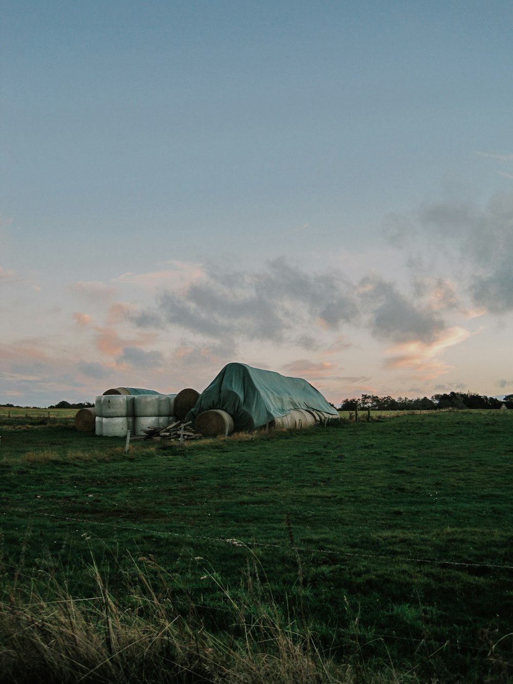 a green field with hay bales in the middle of it