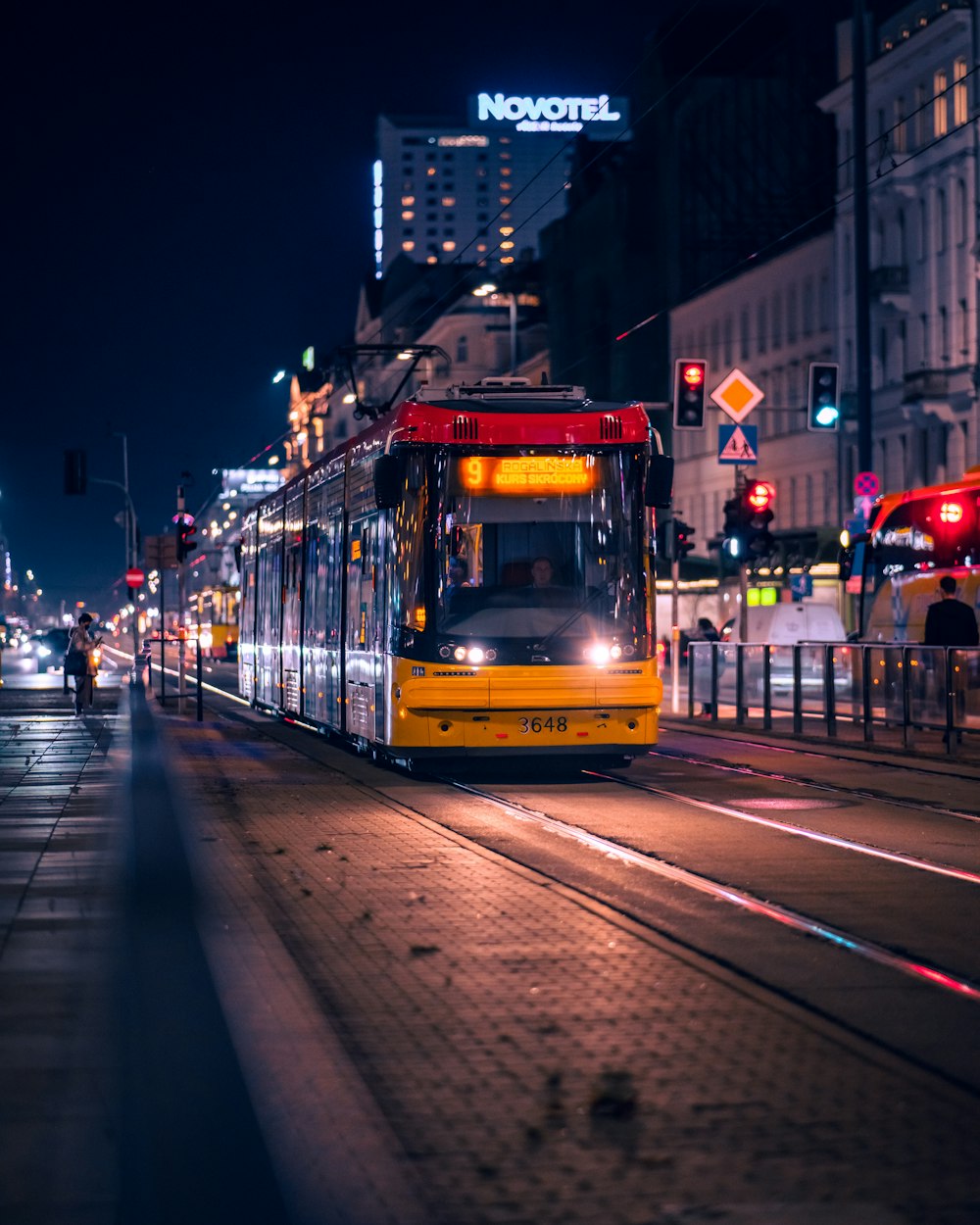 a city street at night with a trolley on the tracks