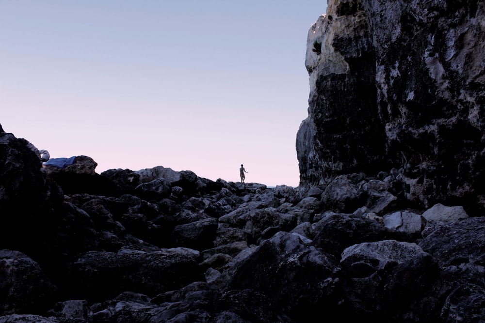une personne debout au sommet d’une montagne rocheuse