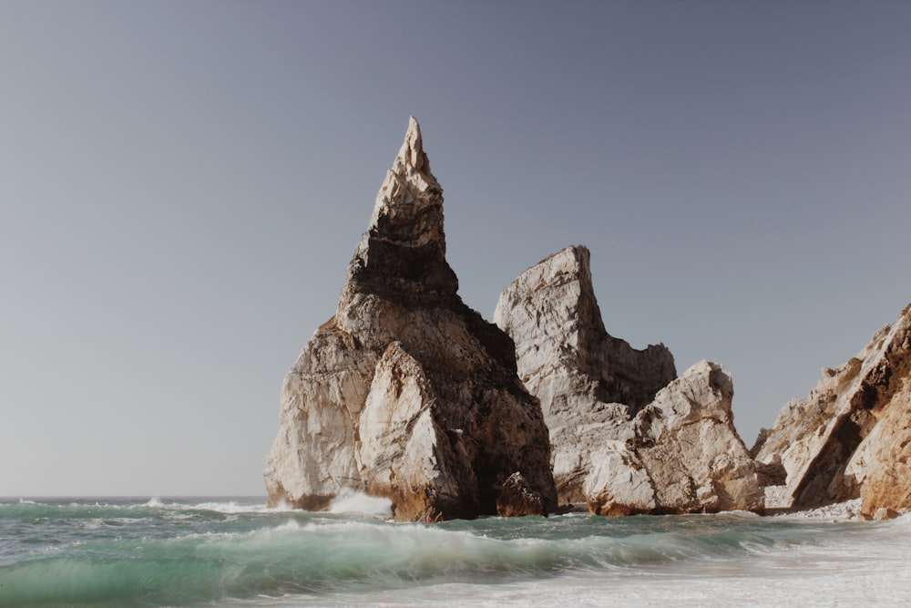 a rock formation in the ocean near a beach