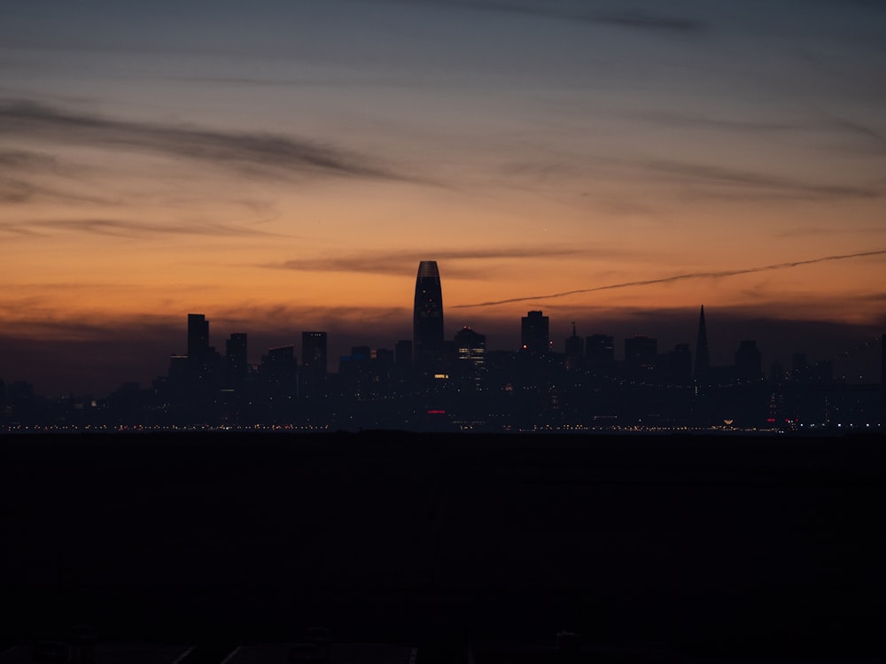 a city skyline at night with a plane flying in the sky