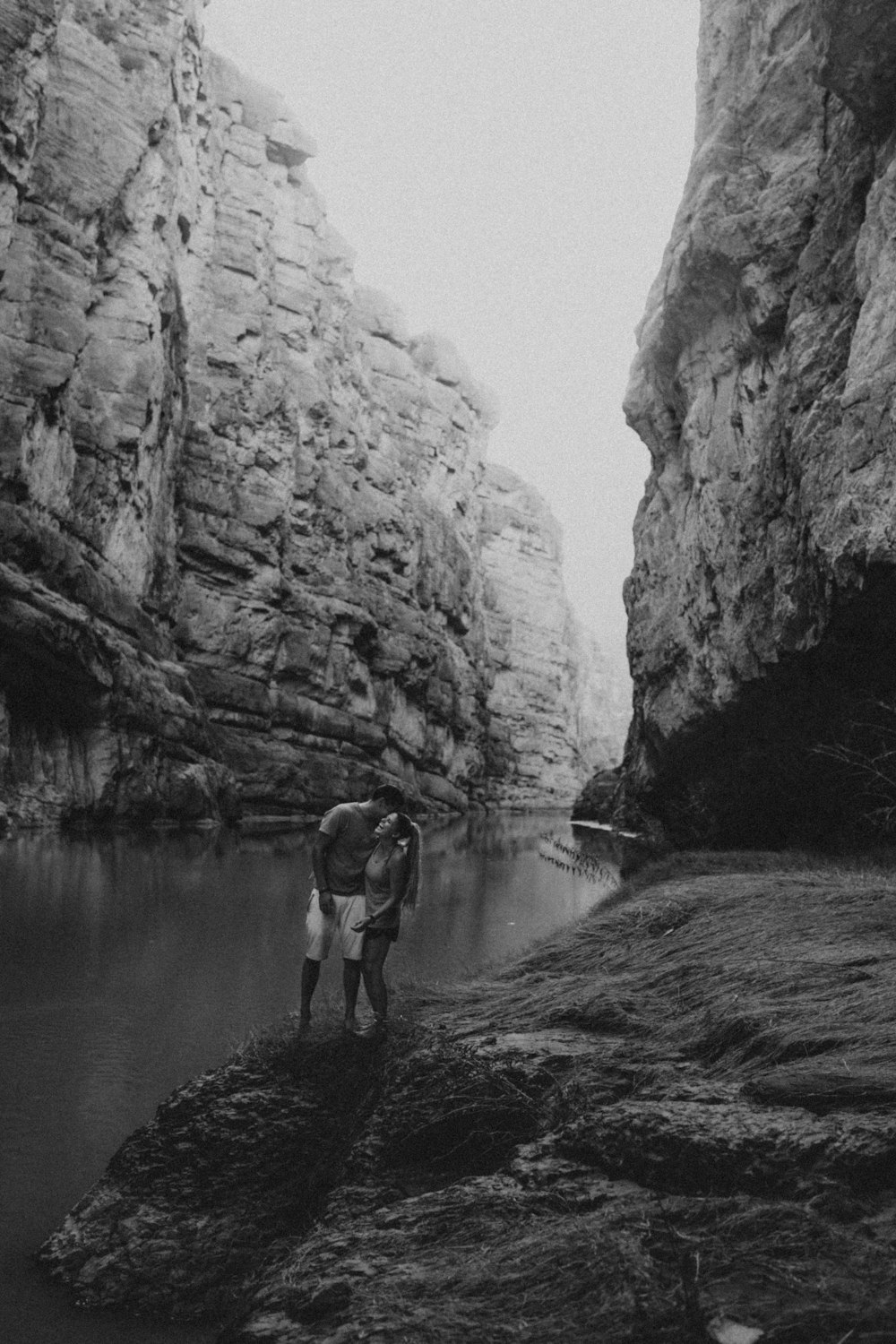Una foto in bianco e nero di un uomo in piedi in un canyon