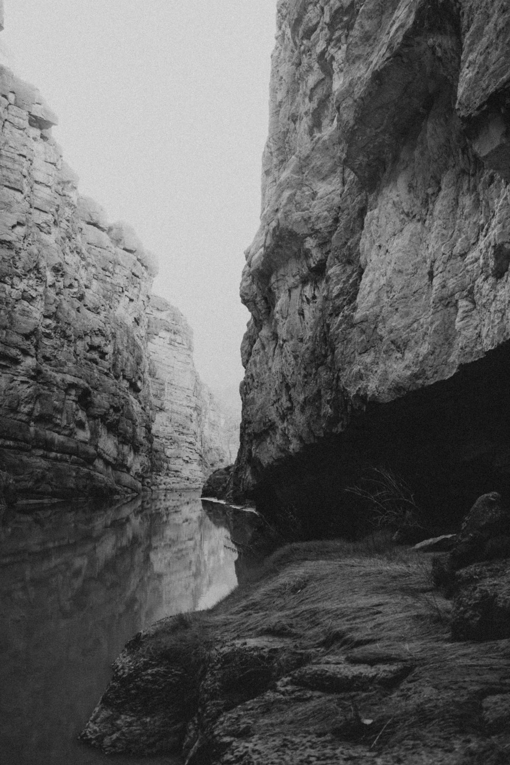 a black and white photo of a narrow river