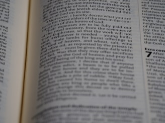 A close-up view of an open book with text in columns, featuring a visible chapter heading on the right page. The text is printed in black on white pages, and the font appears to be of medium size with certain sections in bold.