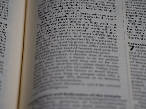 A close-up view of an open book with text in columns, featuring a visible chapter heading on the right page. The text is printed in black on white pages, and the font appears to be of medium size with certain sections in bold.