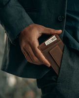 Lifestyle shot of a person slipping a stowly wallet into their jacket pocket on a city street.