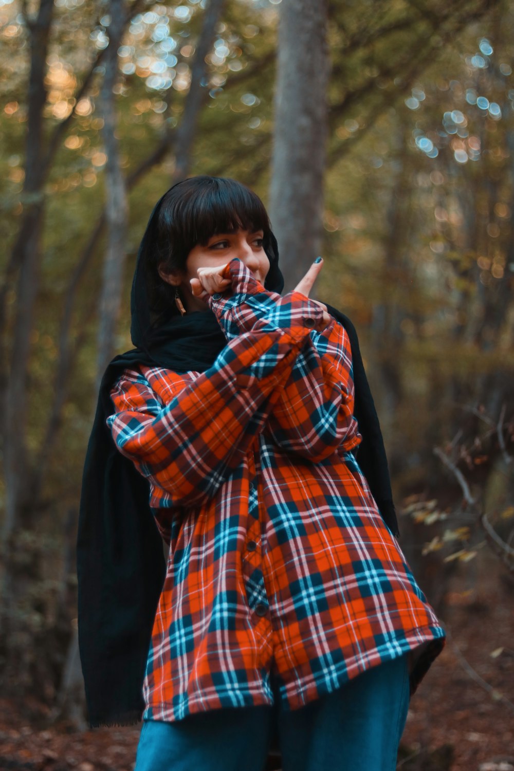 a woman standing in the woods making a peace sign