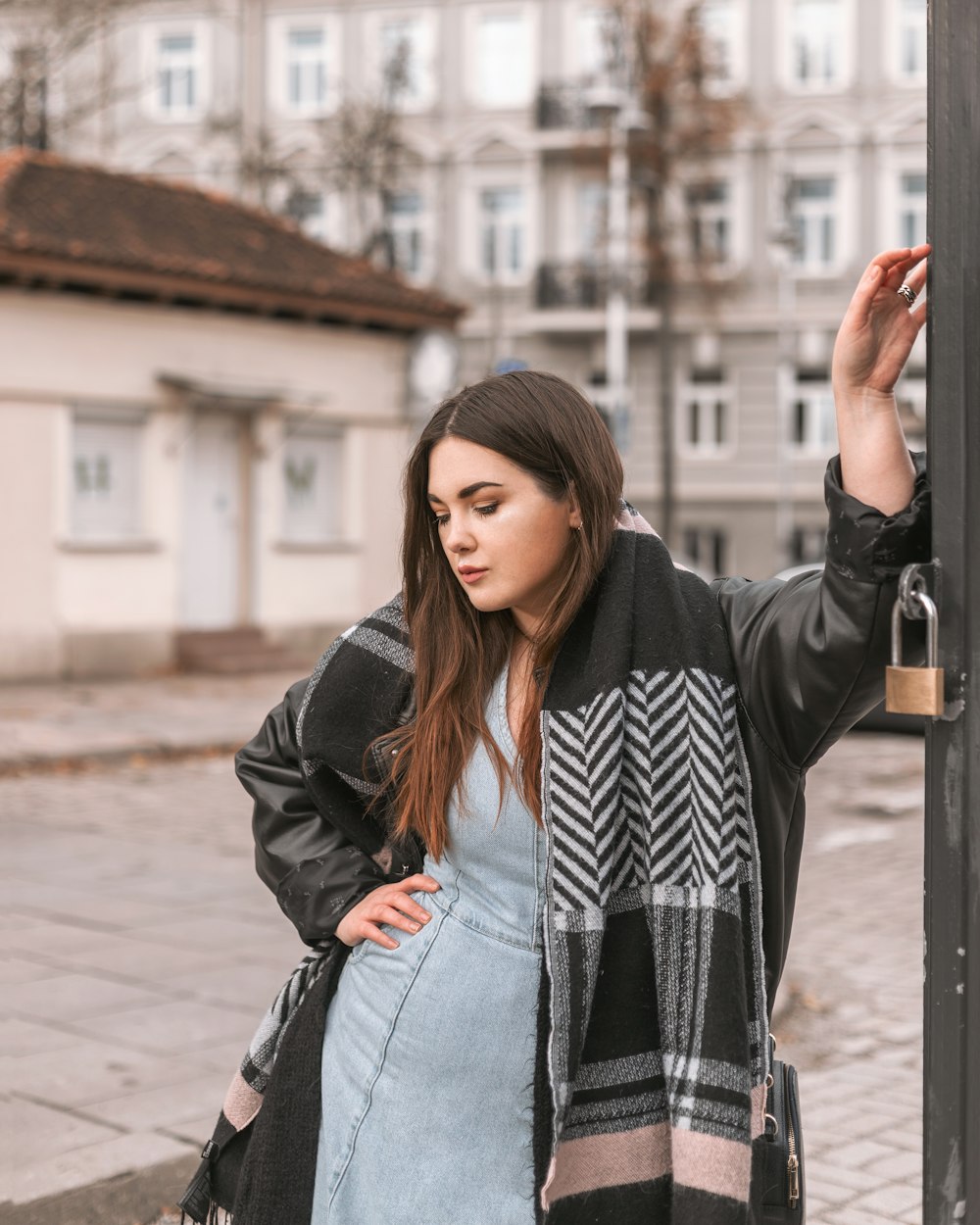 a woman standing next to a pole on a sidewalk