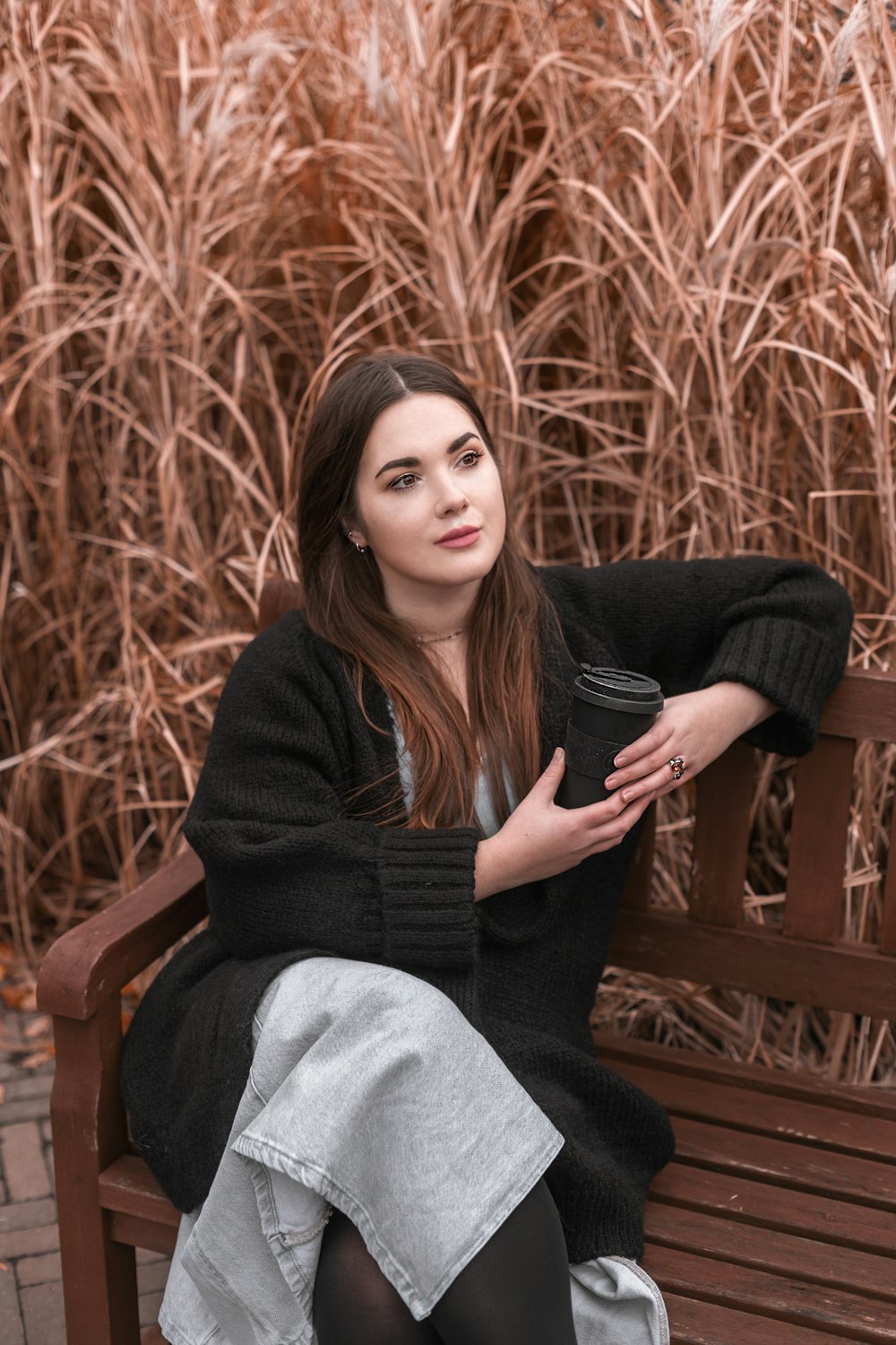 a woman sitting on a bench with a cup of coffee