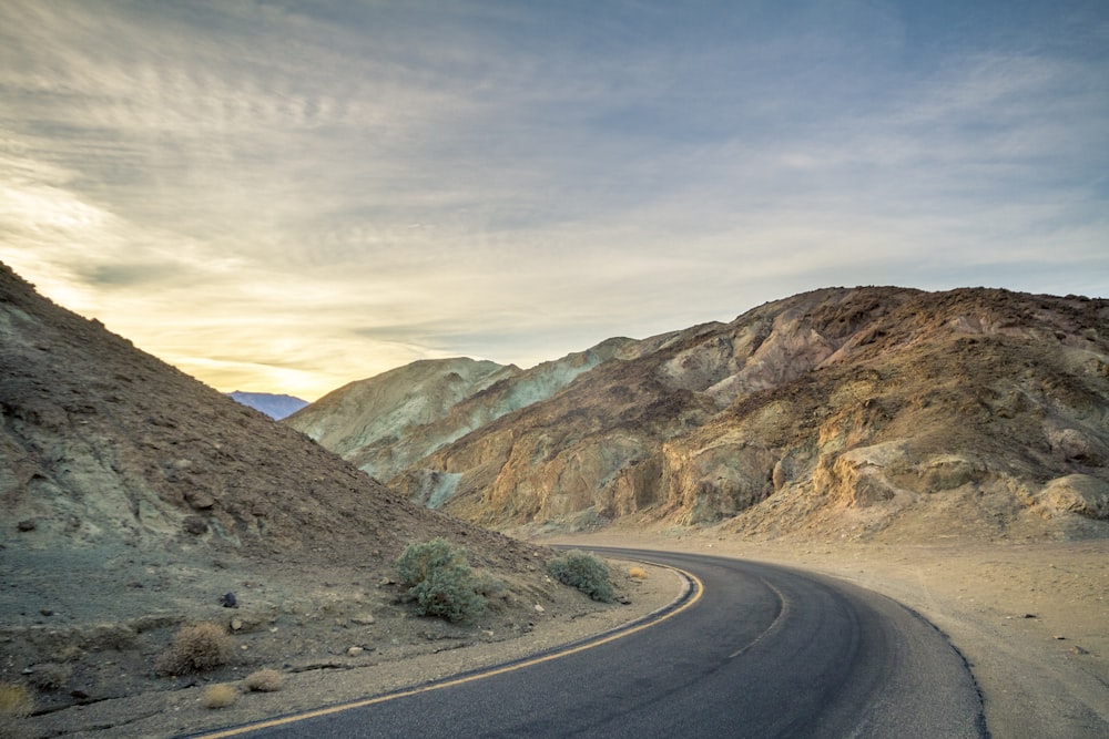 a winding road in the desert with mountains in the background