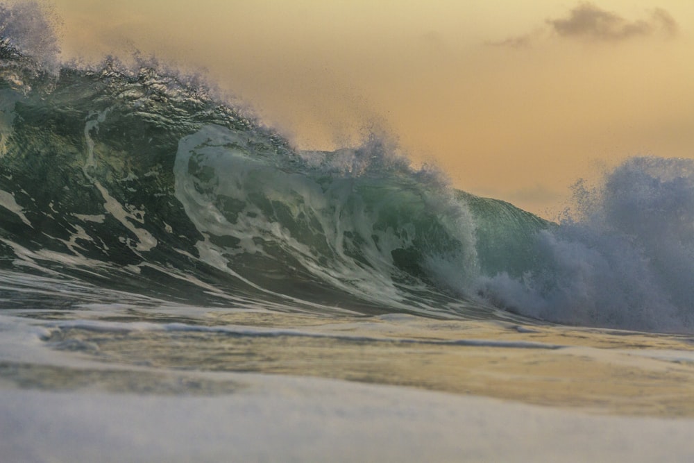 a large wave in the ocean with a sky background