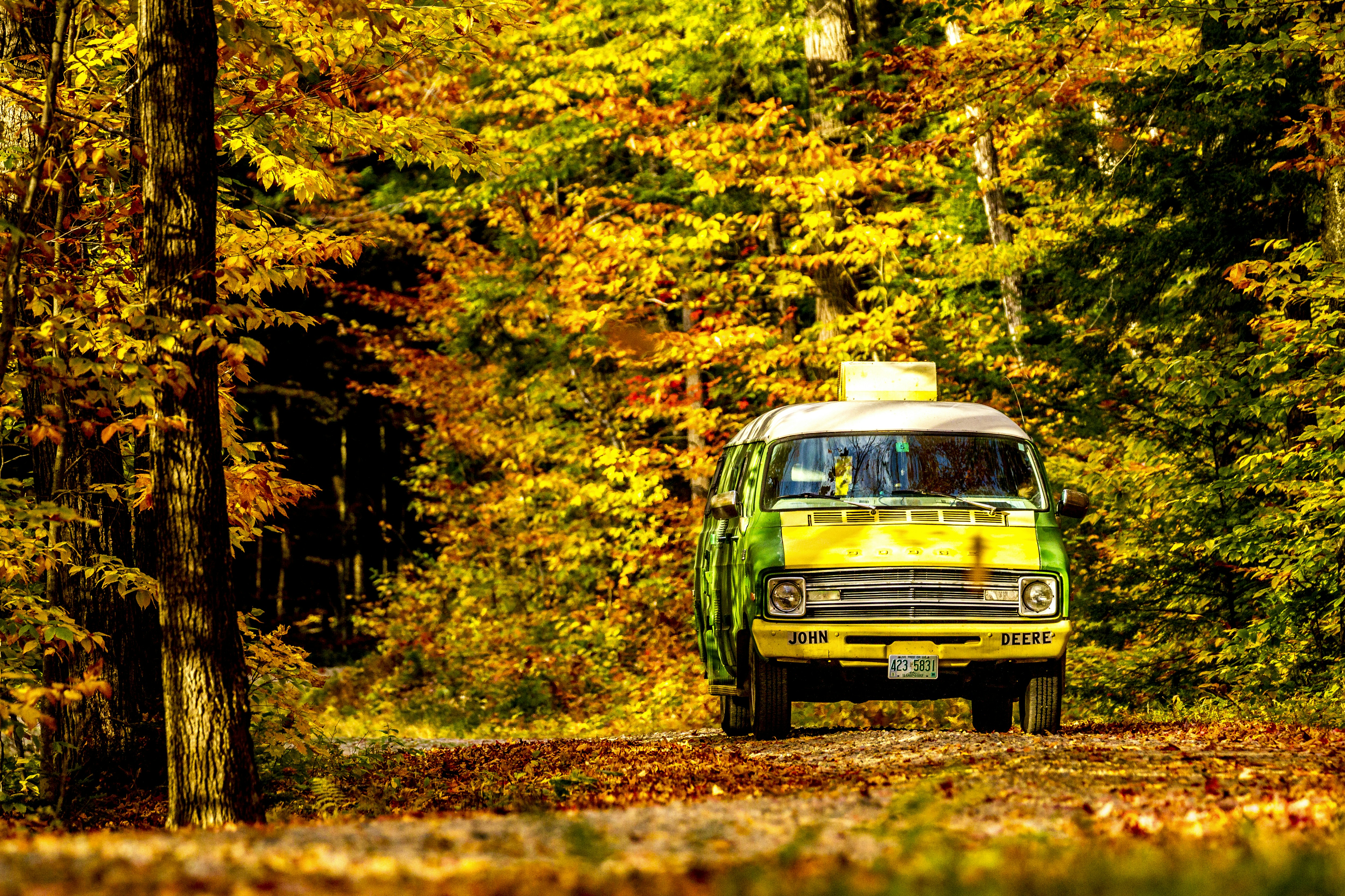 a van is driving down a road in the woods, A classic dodge in classic scenery, driving the Kancamagus Highway as the leaves change for the season. 