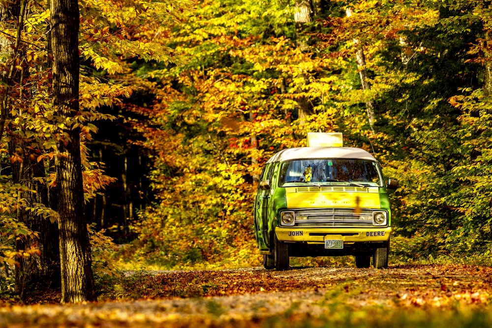 a van is driving down a road in the woods