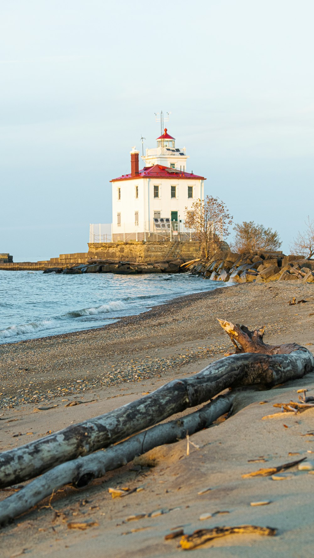 a log laying on a beach next to a light house