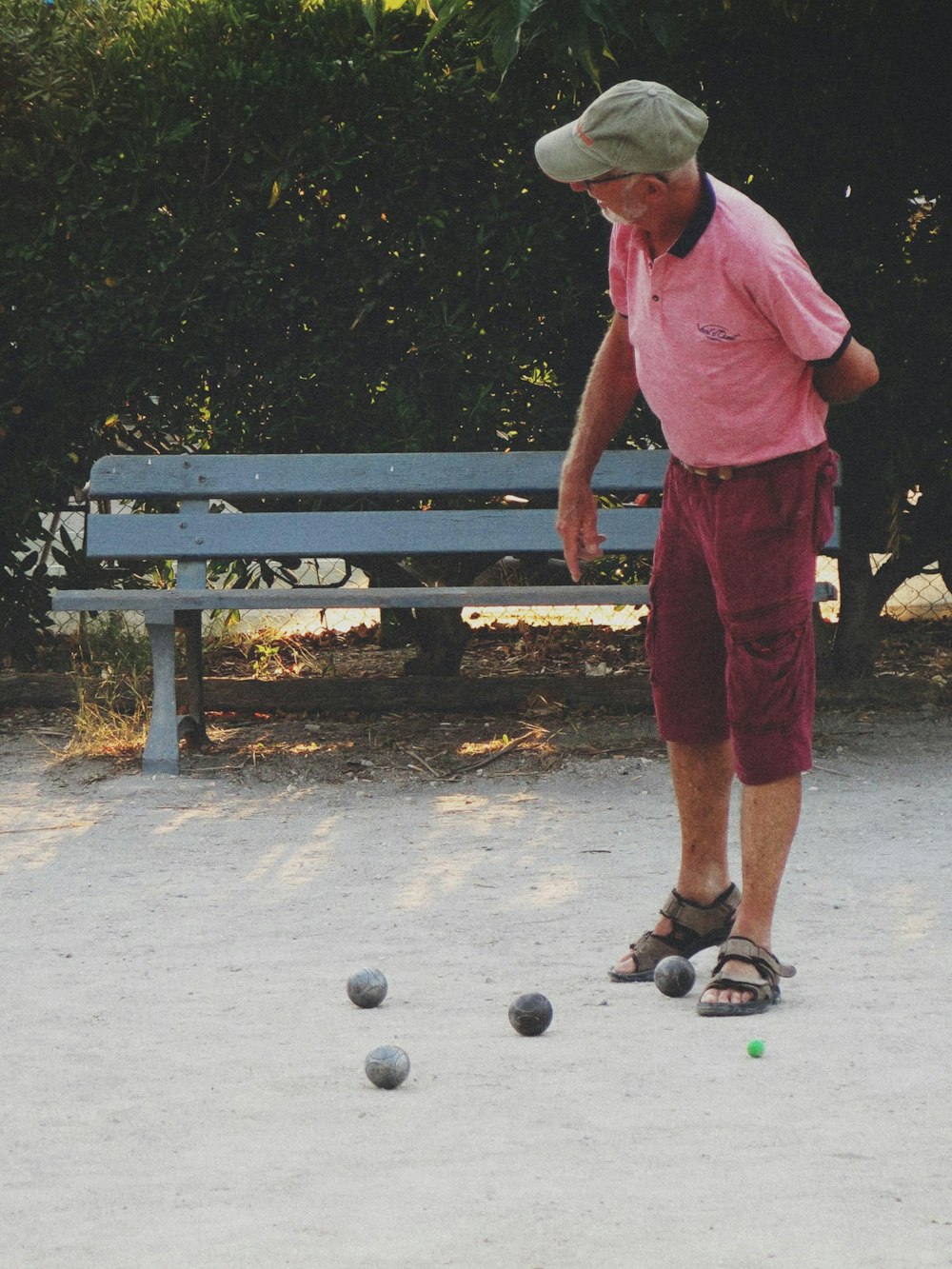 um homem de camisa rosa está brincando com bolas