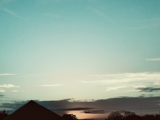 A serene landscape with a sunrise and a house silhouette.
