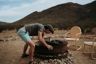 a man bending over a tire on top of a pile of rocks