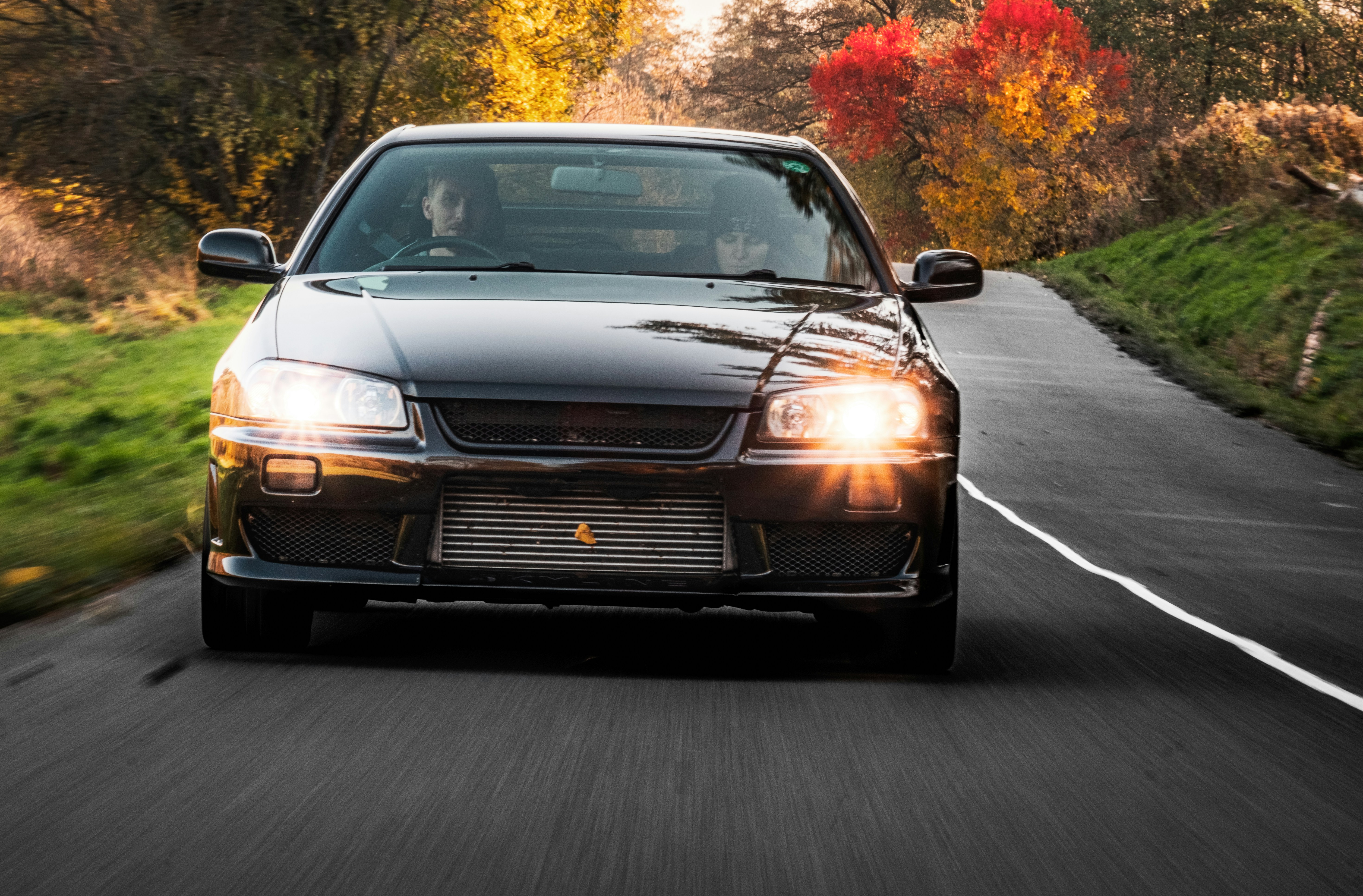 a black car driving down a road next to a forest