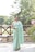 a woman in a green sari standing in front of a tree