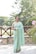 a woman in a green sari standing in front of a tree