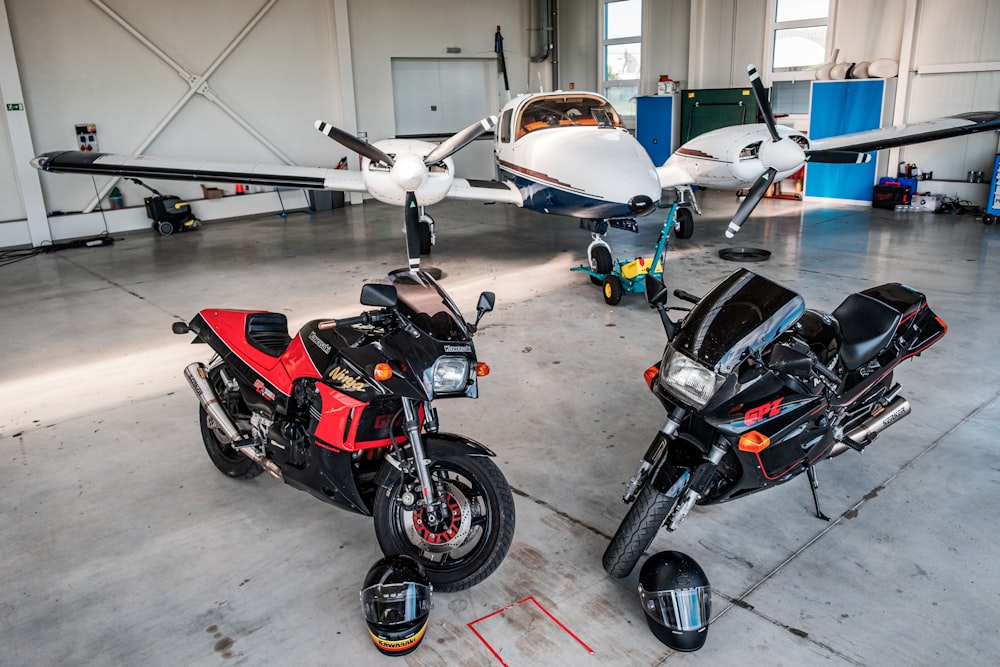two motorcycles parked in a garage next to an airplane