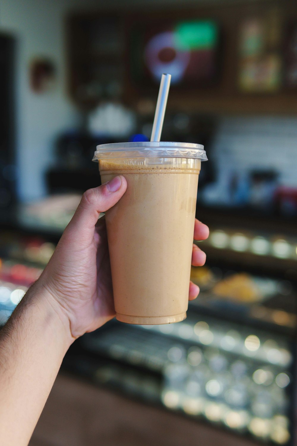 a hand holding a cup with a straw in it