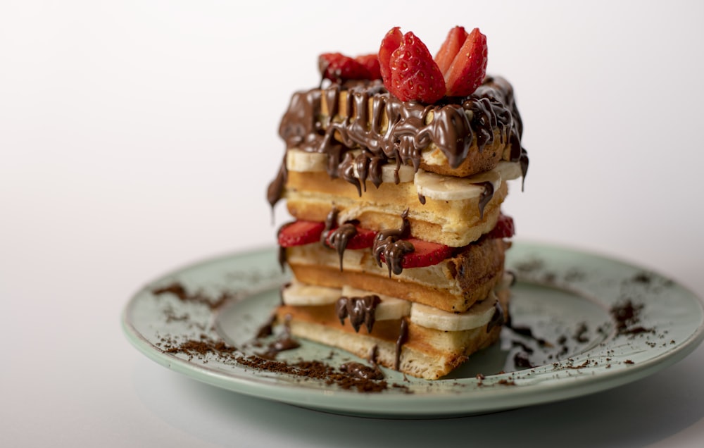 a stack of waffles topped with strawberries and chocolate