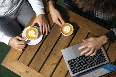 a couple of people sitting at a table with laptops