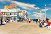 a group of people walking on a boardwalk next to a building