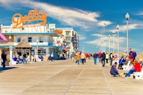 a group of people walking on a boardwalk next to a building