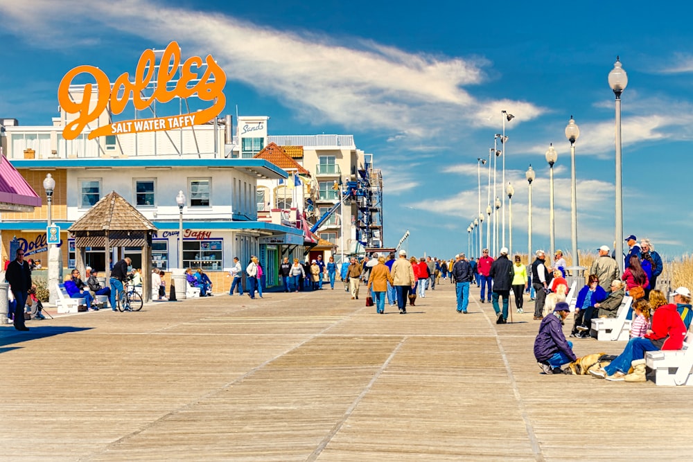 a group of people walking on a boardwalk next to a building