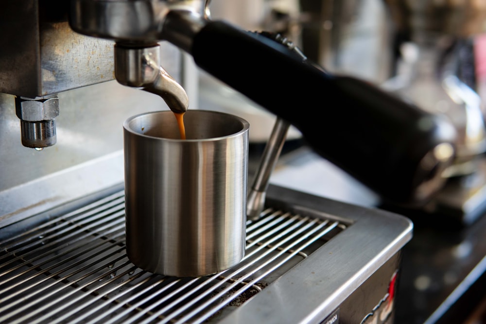 a cup of coffee being poured into a coffee machine