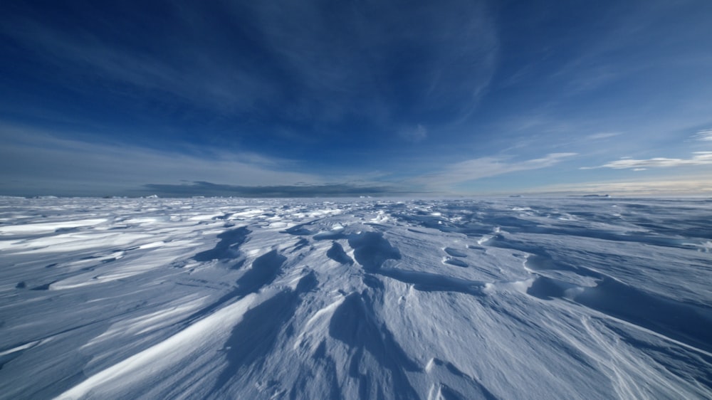 a wide expanse of snow covered ground under a blue sky