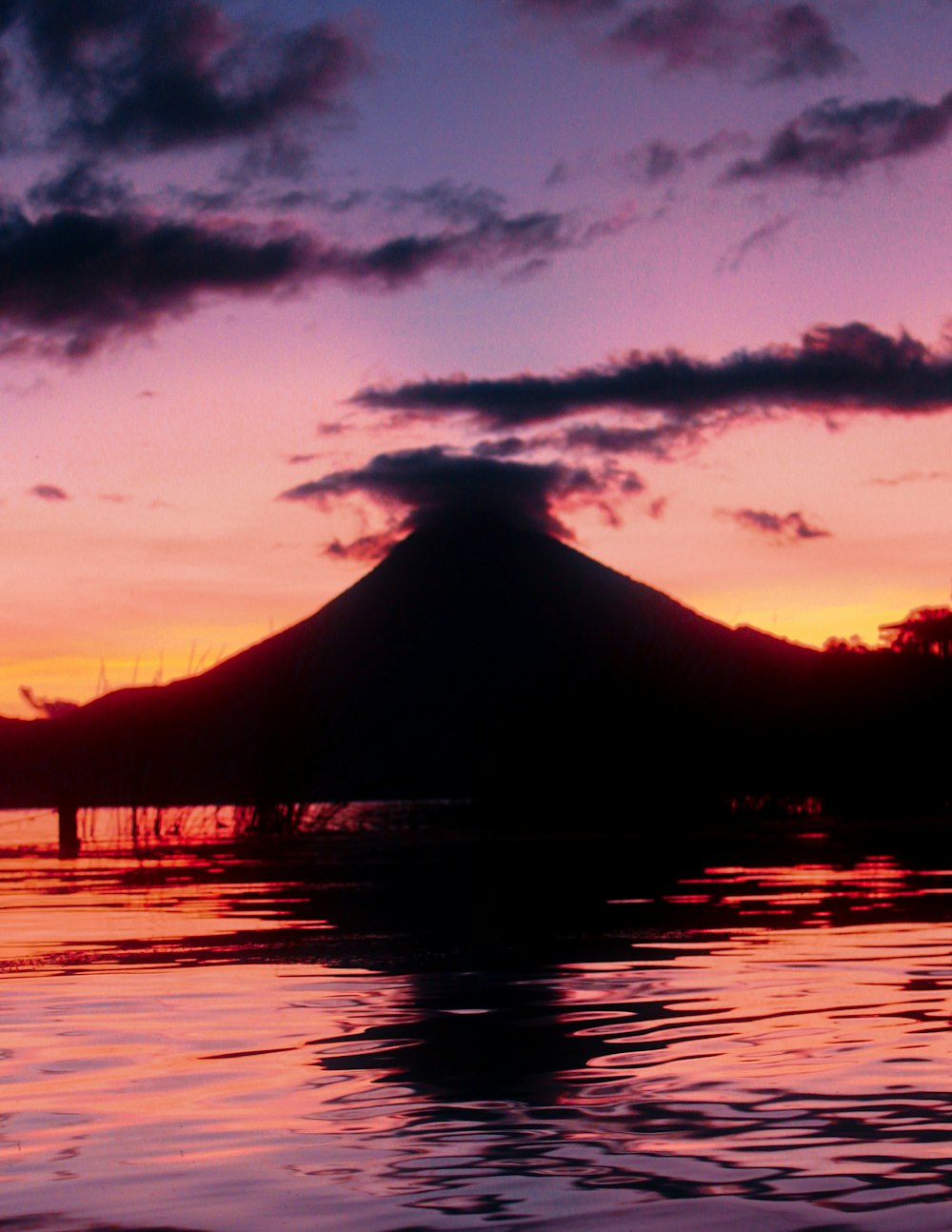 a sunset view of a mountain and a body of water