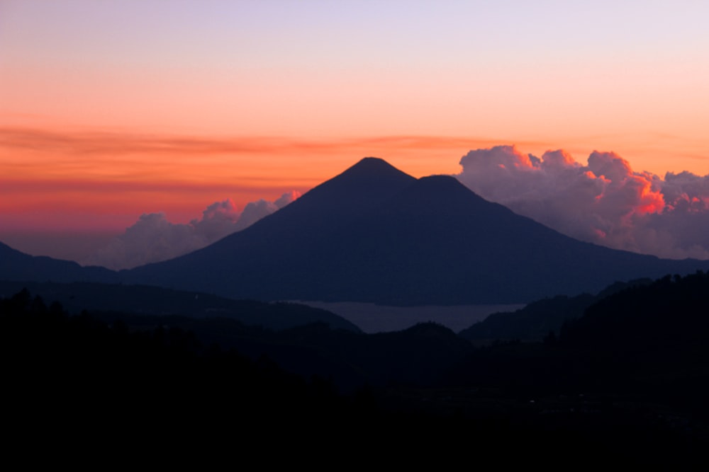 a sunset view of a mountain with clouds in the sky