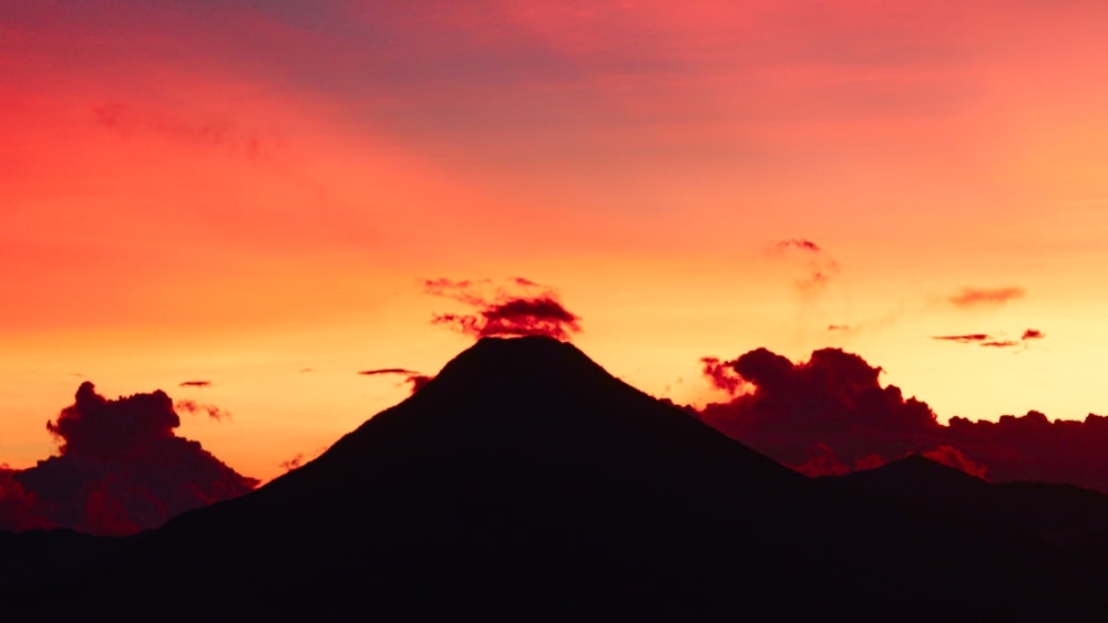 the sun is setting behind a mountain peak